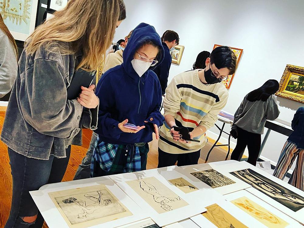 Students look at artwork on a table in the Wright Museum of Art.