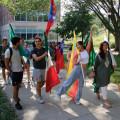 International students lead the Fall 2023 convocation parade, their country's flag in hand.