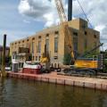 A crane floats on a barge on the Rock River next to the Powerhouse.